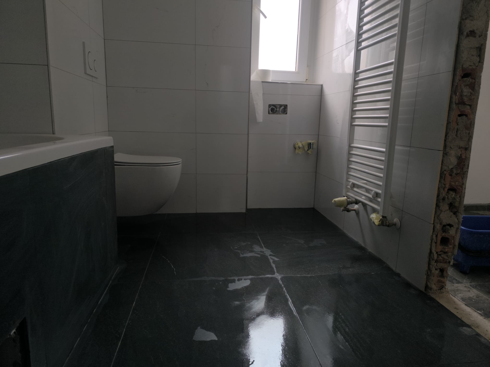 Rekonstrukce koupelny s vanou, světlým obkladem a závěsným WC