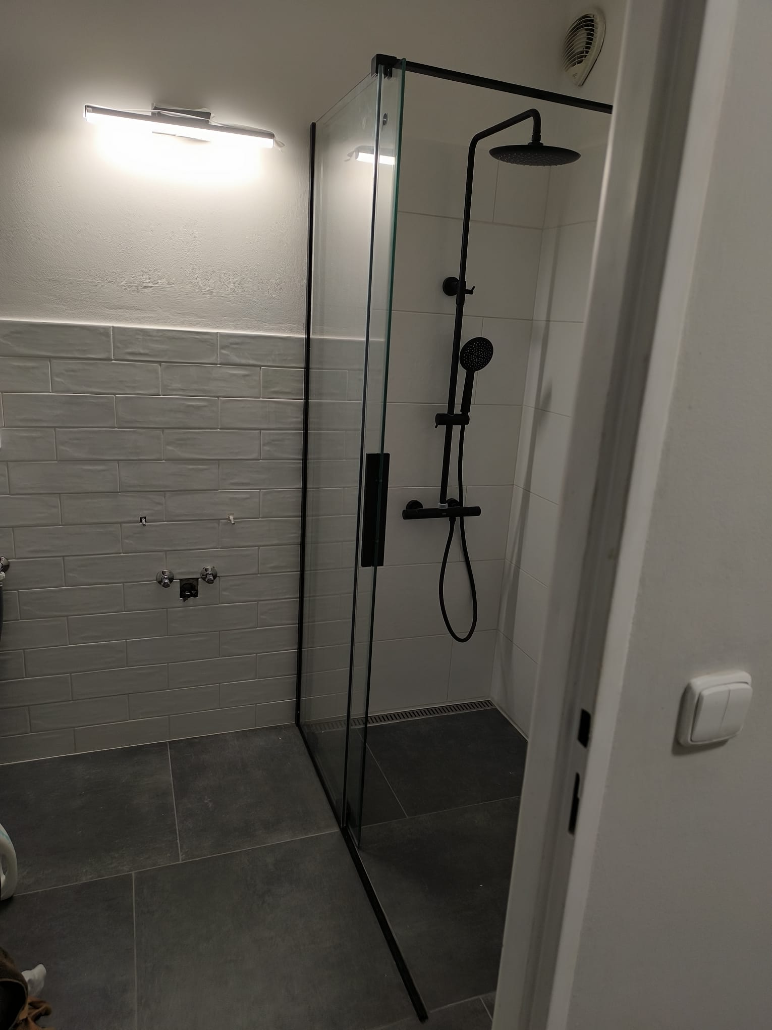 Dokončený sprchový kout se skleněnou zástěnou a černou sprchovou baterií