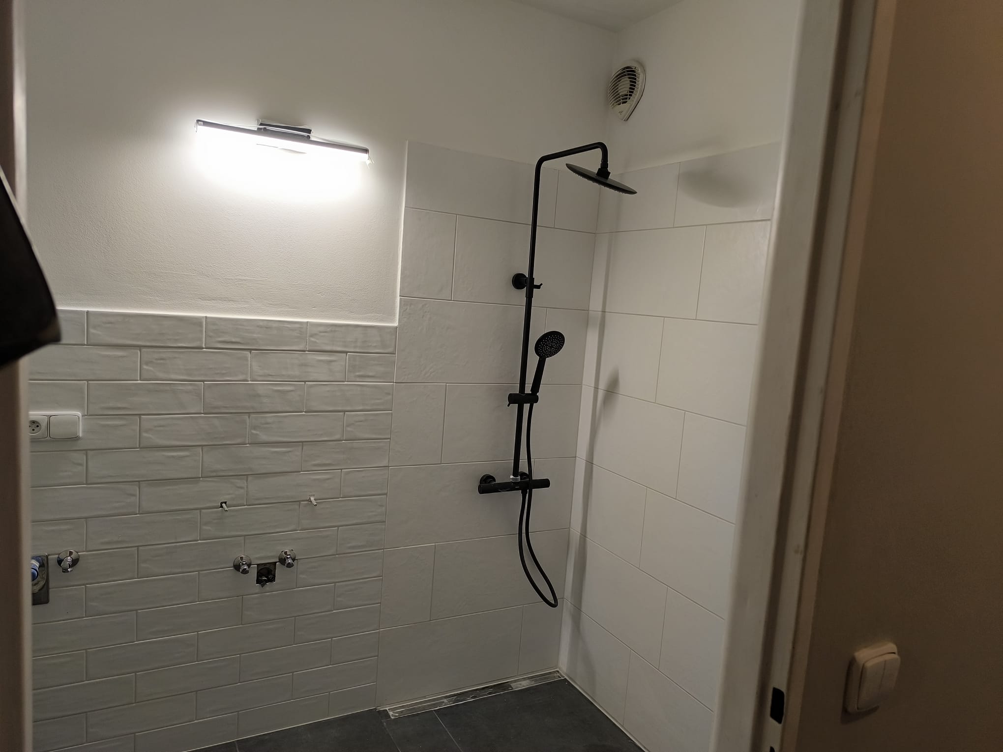 Moderní sprchový kout s černou baterií, šedou dlažbou a liniovým žlabem